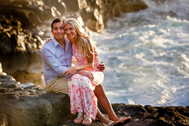 bride and groom sitting on lava rocks at the ocean