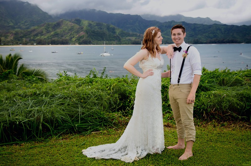 The bride's gown is rain-soaked. But it's warm rain. The grass is spongy. It's Kauai. A wedding photograph on the bluffs of Hanalei Bay. 